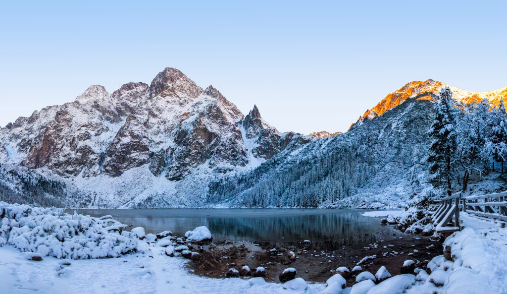 Winter mountains. Snowy mountain on Morskie Oko icy lake. Winter rocks on clear morning. Frosty nature in High Tatra national park, Poland