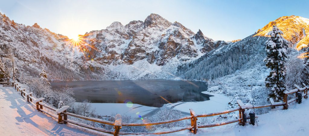 Winter landscape. Winter mountains in morning sunlight. Sunrise with bright sunbeams in snowy frosty mountain. Morskie oko lake in Tatra